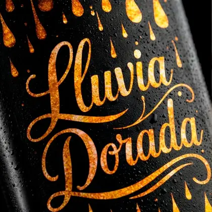 Detalle de la etiqueta de Lluvia Dorada, con letras y gotas doradas sobre la botella negra cubierta de condensación